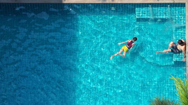 Water streaming corner in swimming pool top view and people enjoyed together on summer vacation day.