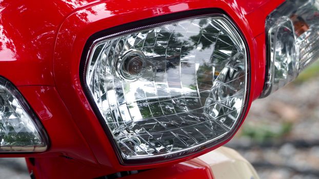 Close-up of motorcycle parts from red and white color old retro japanese bike such as light, start key, hand, fuel tank and button.