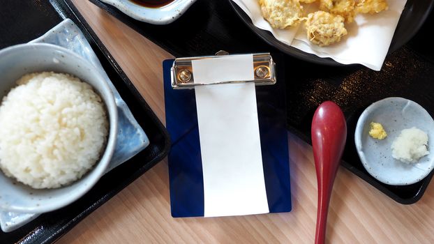 White blank receipt paper bill for payment and food on the japnese restaurant table top view angle.