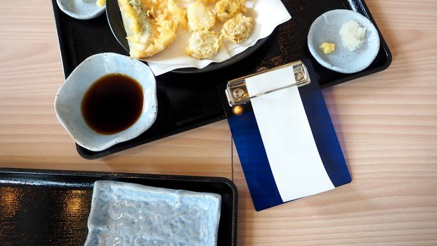 White blank receipt paper bill for payment and food on the japnese restaurant table top view angle.