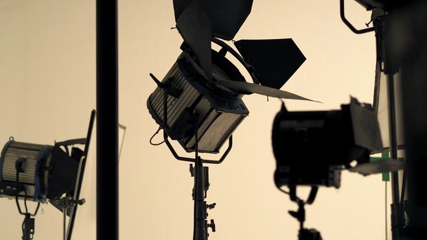 Big studio flash light on tripod and soft box paper in large size studio for video or film production.