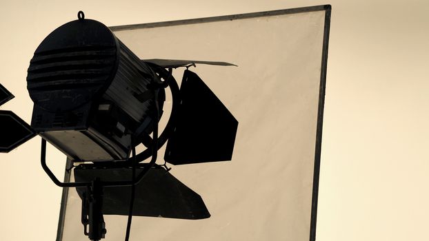 Big studio flash light on tripod and soft box paper in large size studio for video or film production.