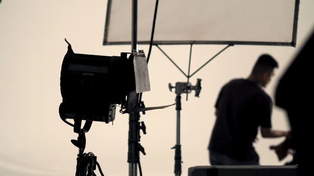 Big studio flash light on tripod and soft box paper in large size studio for video or film production.