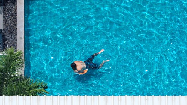 Swimming pool blue color clear water and people enjoying in summer sunny day and top view angle.