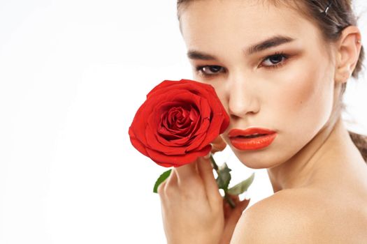 Beautiful woman with red rose near face makeup naked shoulders portrait. High quality photo