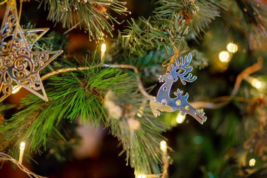 Christmas decoration in the form of a galloping deer on a Christmas tree. Golden deer, Christmas tree toy on a branch of a festive tree