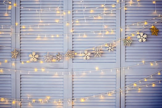 Christmas decoration on the wall. Wooden Christmas garland and lanterns. Texture or background for postcards. Wooden snowflakes