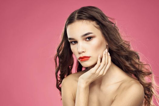 Attractive woman fashionable hairstyle bared shoulders and red lips pink background. High quality photo