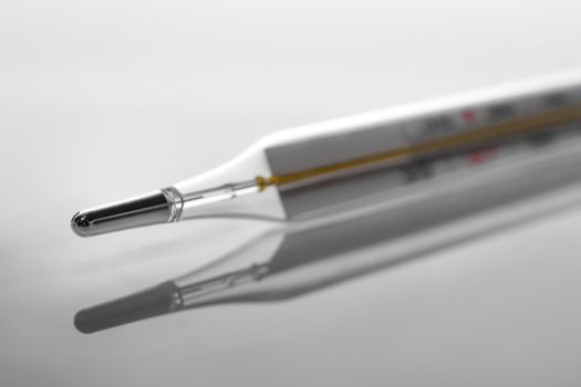 Mercury thermometer. Selective focus, gray background