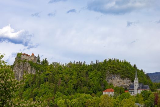 Slovenia, Bled Castle surrounded by green spring forest. Cloudy sky