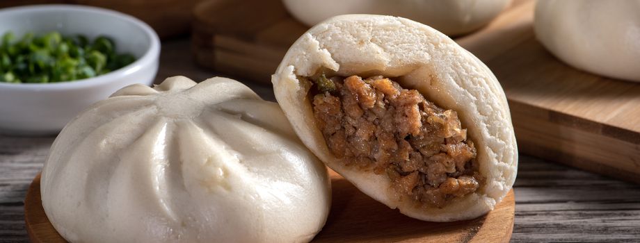 Close up of fresh delicious baozi, Chinese steamed meat bun is ready to eat on serving plate and steamer, close up, copy space product design concept.