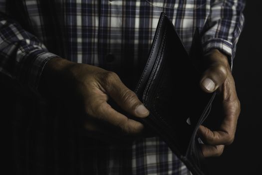 Close-up for a man standing and holding empty wallet. Wallet out of money.