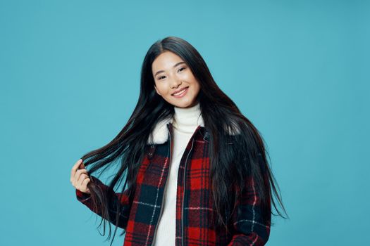 Asian woman in jacket on blue background close-up portrait