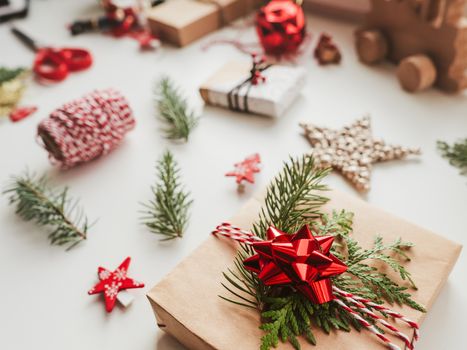 Christmas DIY presents wrapped in craft paper with fir tree branches. Red threads and bow. New Year gifts. Festive background. Winter holiday spirit.