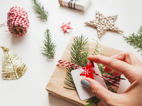 DIY presents wrapped in craft paper with fir tree twigs and red symbol of Christmas tree. Top view on decorations on New Year gifts. Festive background. Winter holiday spirit.