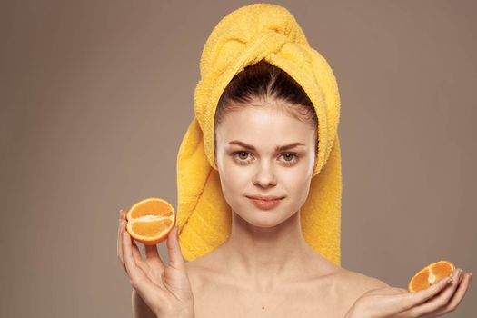 Woman with oranges in hands emotions naked shoulders towel on head beige background. High quality photo