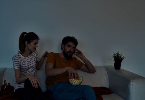 emotional woman and man with a plate of popcorn watching tv in the evening indoors. High quality photo