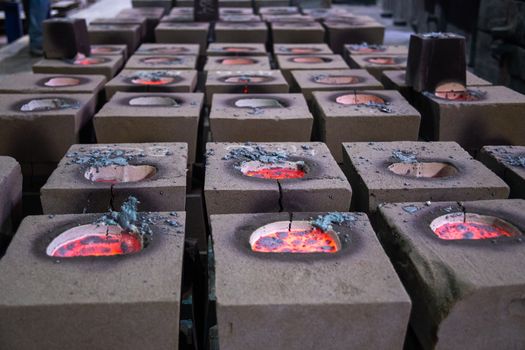 Cooling process of filled sand molds after steel casting, cracked during the process. Close-up view on rows on the factory floor.
