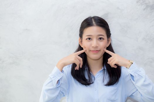 Portrait of beautiful young asian woman happiness standing touch cheek on gray cement texture grunge wall background, businesswoman is a smiling on concrete, business people concept.