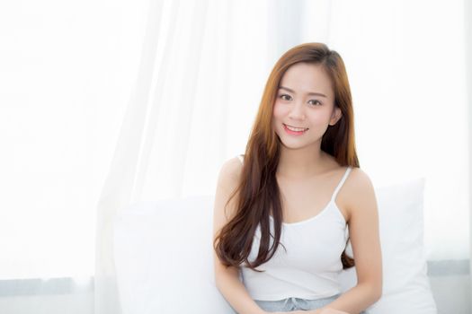 Portrait beautiful young asian woman sitting and smile the window at bedroom while wake up with sunrise at morning, lifestyle and relax concept.