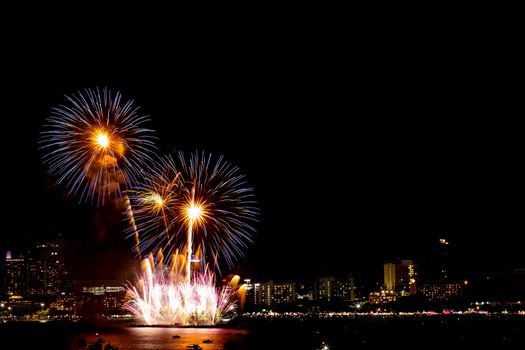 Many flashing fireworks with night cityscape background celebrate New Year.