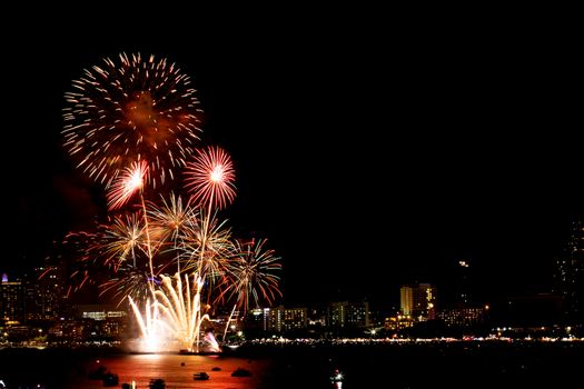 Many flashing fireworks with night cityscape background celebrate New Year.