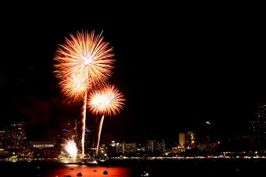Many flashing fireworks with night cityscape background celebrate New Year.