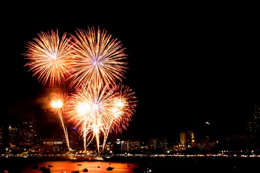 Many flashing fireworks with night cityscape background celebrate New Year.
