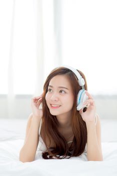Beautiful asian young woman enjoy listen music with headphone while lying in bedroom, relax girl with earphone internet online, leisure and technology concept.
