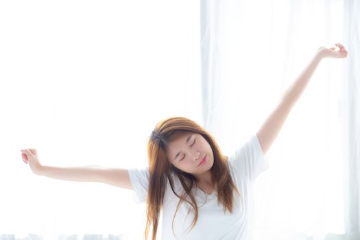 Beautiful of portrait young asian woman stretch and relax in bed after wake up morning at bedroom, new day and resting for wellness, lifestyle concept.