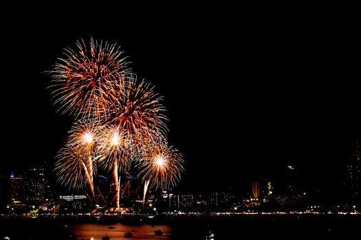 Many flashing fireworks with night cityscape background celebrate New Year.