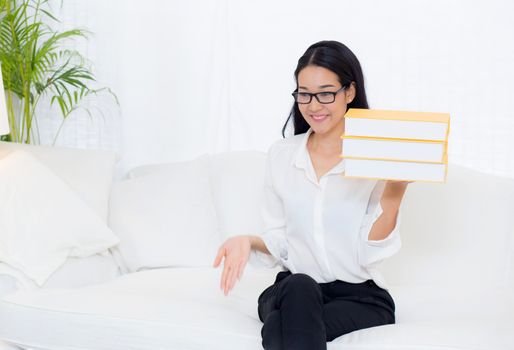 portrait of a beautiful young asian woman read book on couch in living room - education concept.