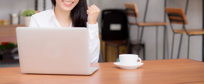 Closeup banner website asian young businesswoman excited and glad of success with laptop, girl using working computer coffee shop on desk, career freelance business concept.