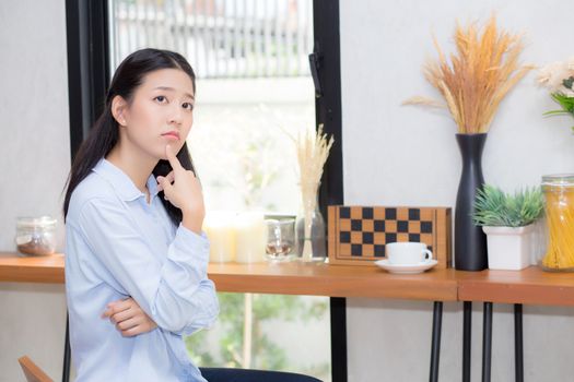 Portrait of beautiful young asian woman happiness and think sitting at cafe shop, businesswoman is a smile, freelance people concept.