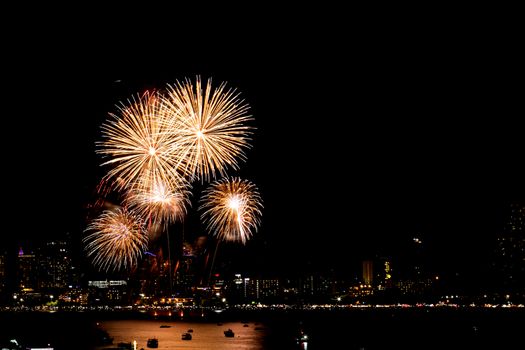 Many flashing fireworks with night cityscape background celebrate New Year.