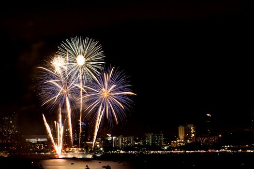 Many flashing fireworks with night cityscape background celebrate New Year.
