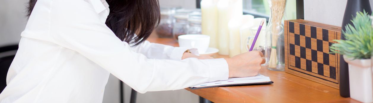 Closeup banner website business asian young woman writing on notebook on table, girl work at coffee shop, freelance business concept.