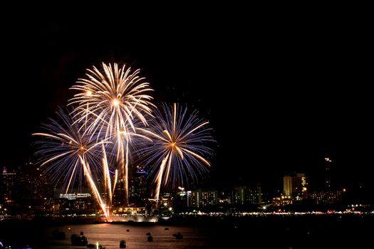 Many flashing fireworks with night cityscape background celebrate New Year.