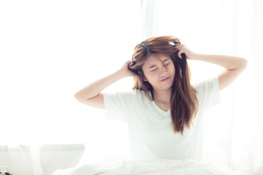 Beautiful young asian woman stretch and relax in bed after wake up morning at bedroom, back view, new day and resting for wellness, lifestyle concept.