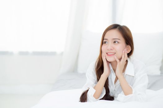 Beautiful portrait young asian woman lying and smile while wake up with sunrise at morning, lifestyle and relax concept.