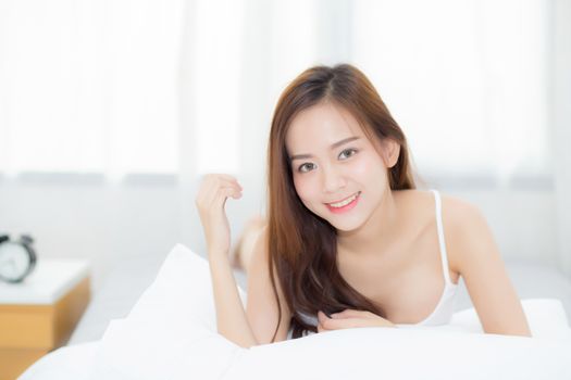 Beautiful portrait young asian woman lying and smile while wake up with sunrise at morning, lifestyle and relax concept.