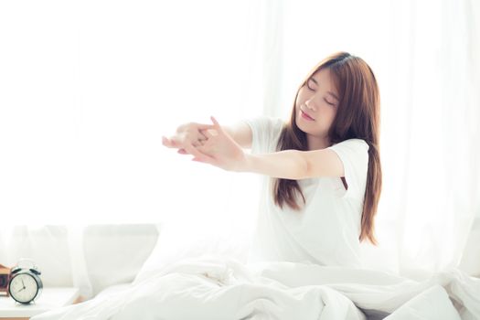 Beautiful young asian woman stretch and relax in bed after wake up morning at bedroom, back view, new day and resting for wellness, lifestyle concept.
