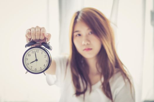 Beautiful asian young woman wake up in morning annoyed alarm clock holding hand, girl hurry wake late with appointment, lifestyle concept.