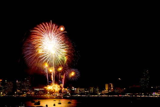 Many flashing fireworks with night cityscape background celebrate New Year.