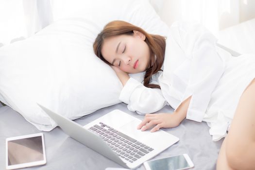 Beautiful young asian woman with laptop lying down in bedroom, girl tired sleep with computer notebook and tablet, resting and healthcare concept. 