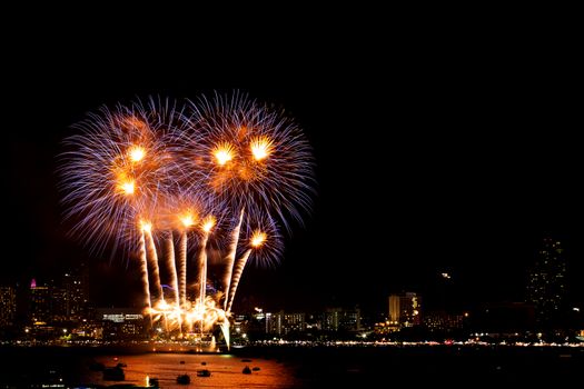 Many flashing fireworks with night cityscape background celebrate New Year.