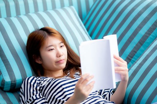 Beautiful of portrait young asian woman relax lying reading book on sofa in bedroom at home, girl study literature, education and lifestyle concept.