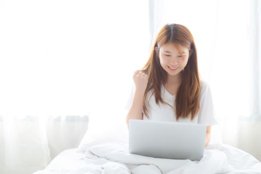 Beautiful happiness young asian woman using laptop work with success on bed in the home, girl and notebook shopping online with glad, communication concept.