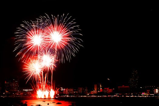 Many flashing fireworks with night cityscape background celebrate New Year.