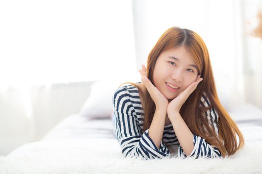 Beautiful portrait young asian woman lying and smile while wake up with sunrise at morning, lifestyle and relax concept.
